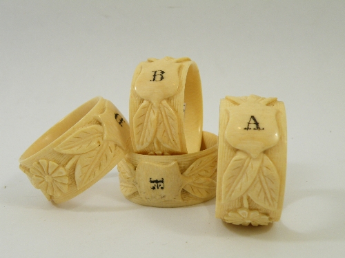Four 19th Century ivory serviette rings each heavily carved with band of flowers and leaves and