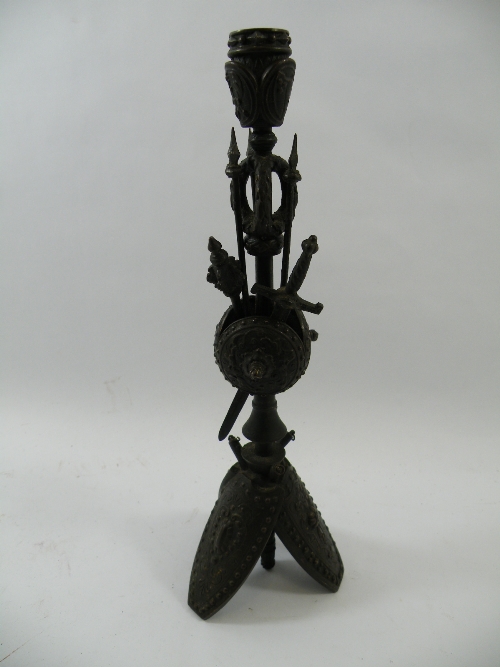 A 19th C bronze armorial candlestick, the base comprising three leaning shields, the main column