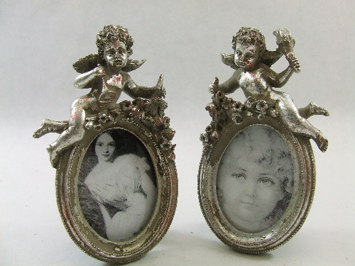Pair of decorative oval picture frames with silver leaf putti 17cm tall