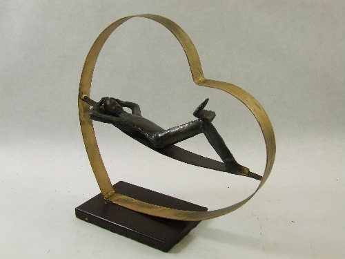 An interesting 20thC stylised modernist sculpture of a man reclining in a heart, formed from