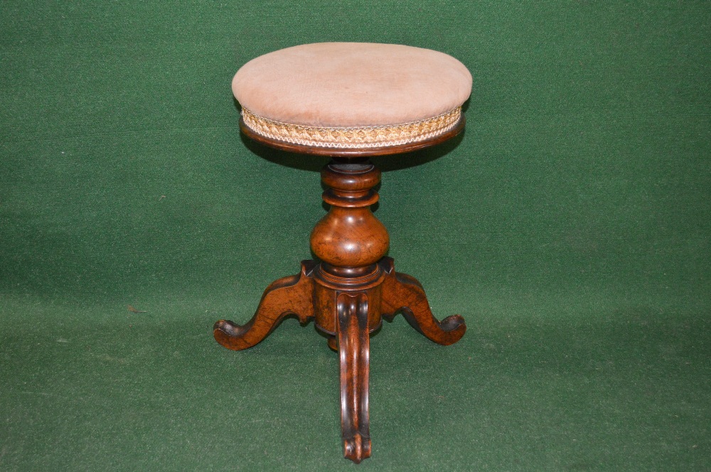 A Victorian mahogany circular revolving piano stool with padded seat supported by bulbous column and