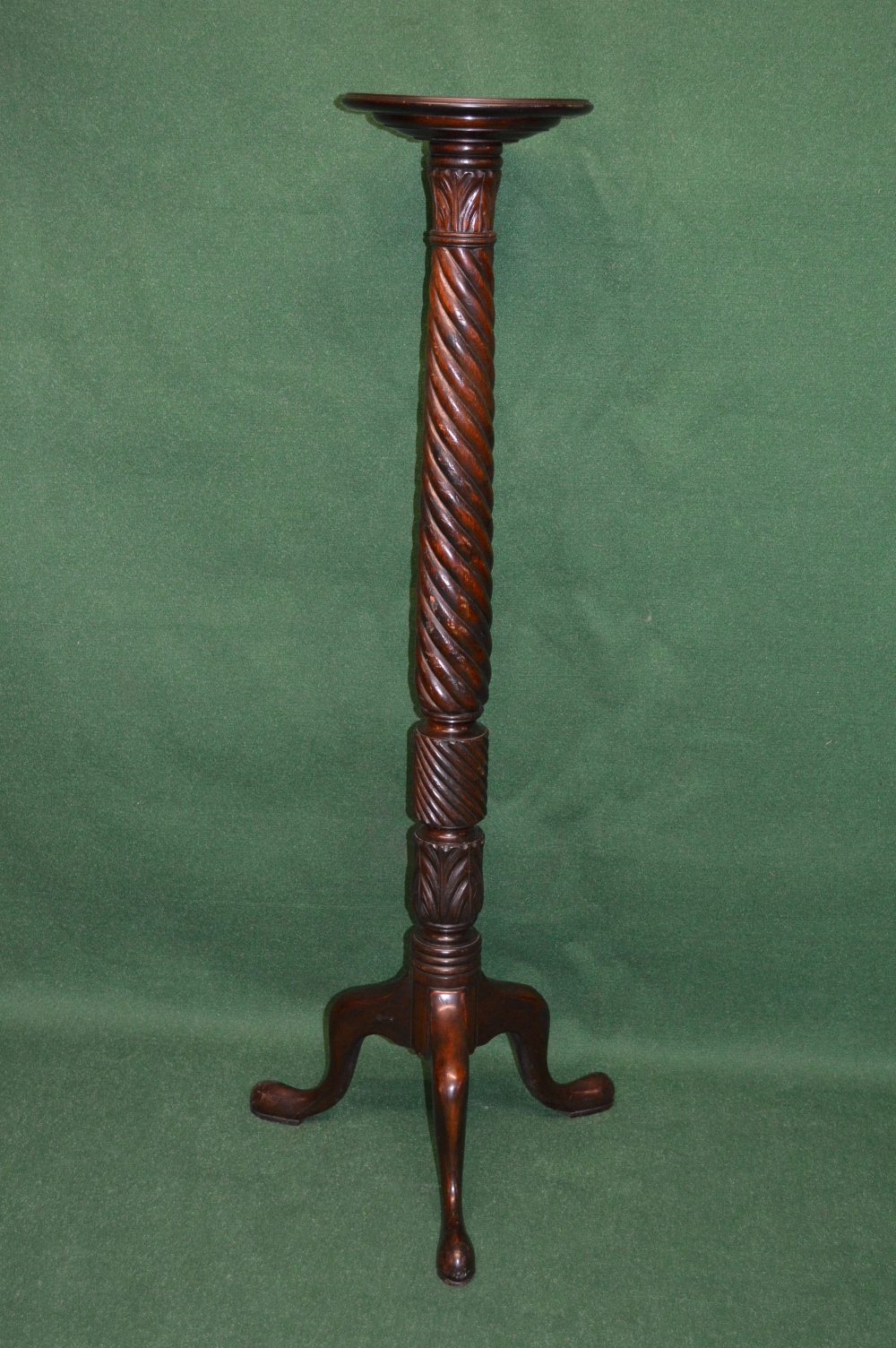 A mahogany torchere having circular top supported by twist and carved column ending in cabriole legs