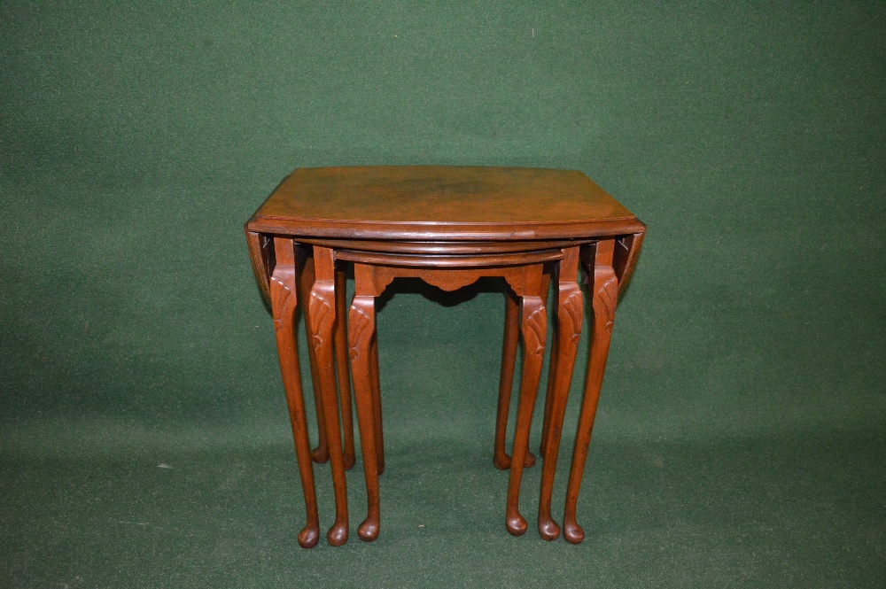 A nest of three walnut occasional tables, the largest having curved drop flaps and standing on