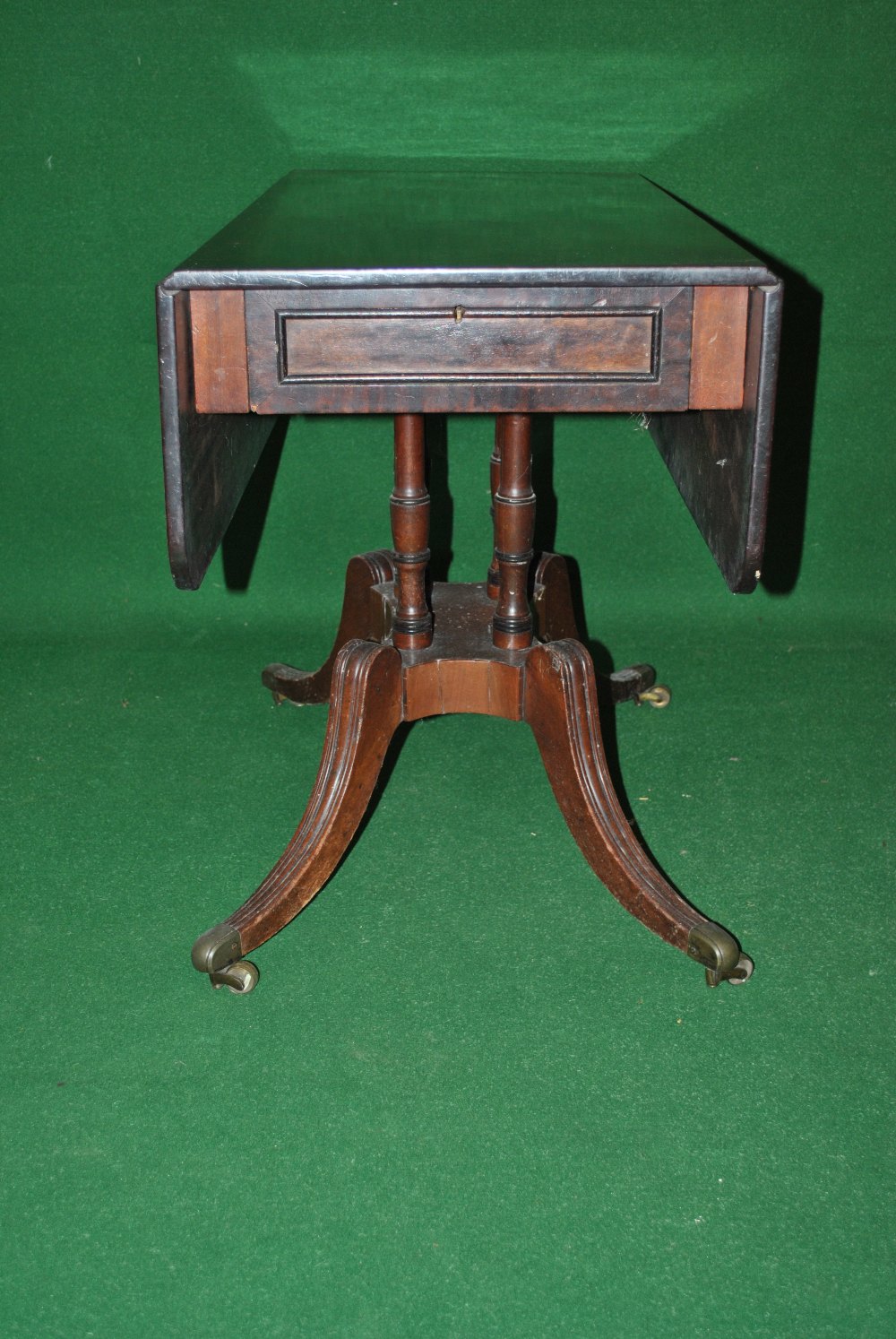 A mahogany Pembroke table having single drawer supported by four central turned columns and standing