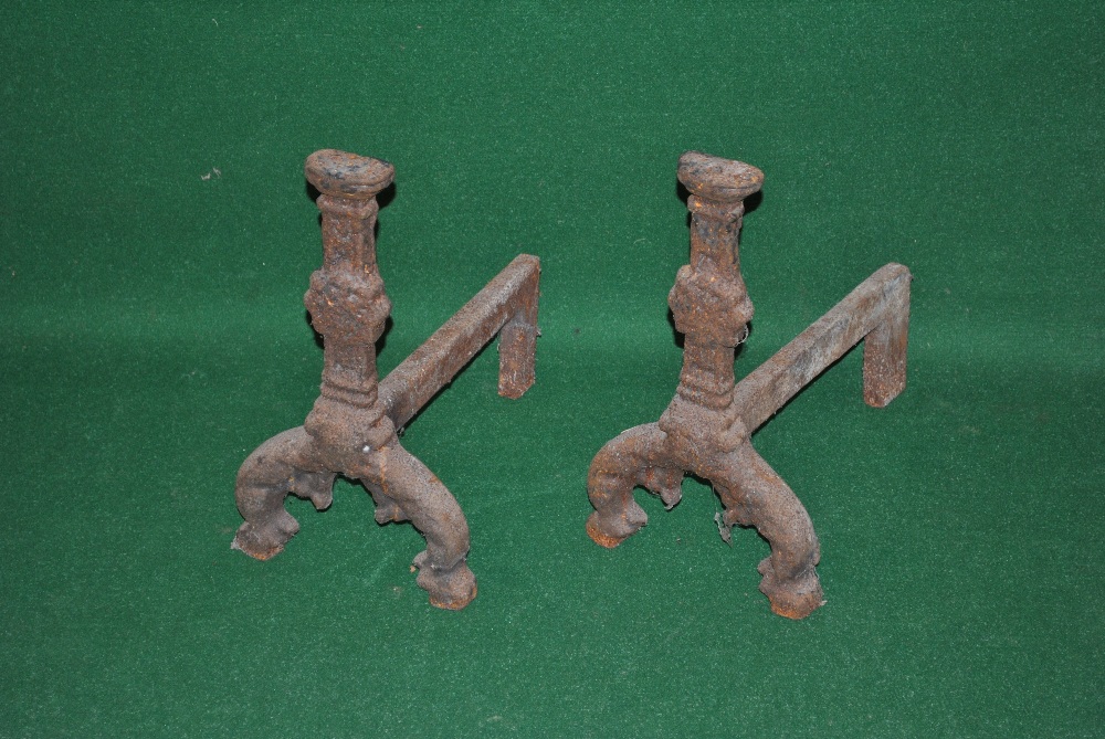 A pair of cast iron fire dogs having rose head motif and standing on scroll feet