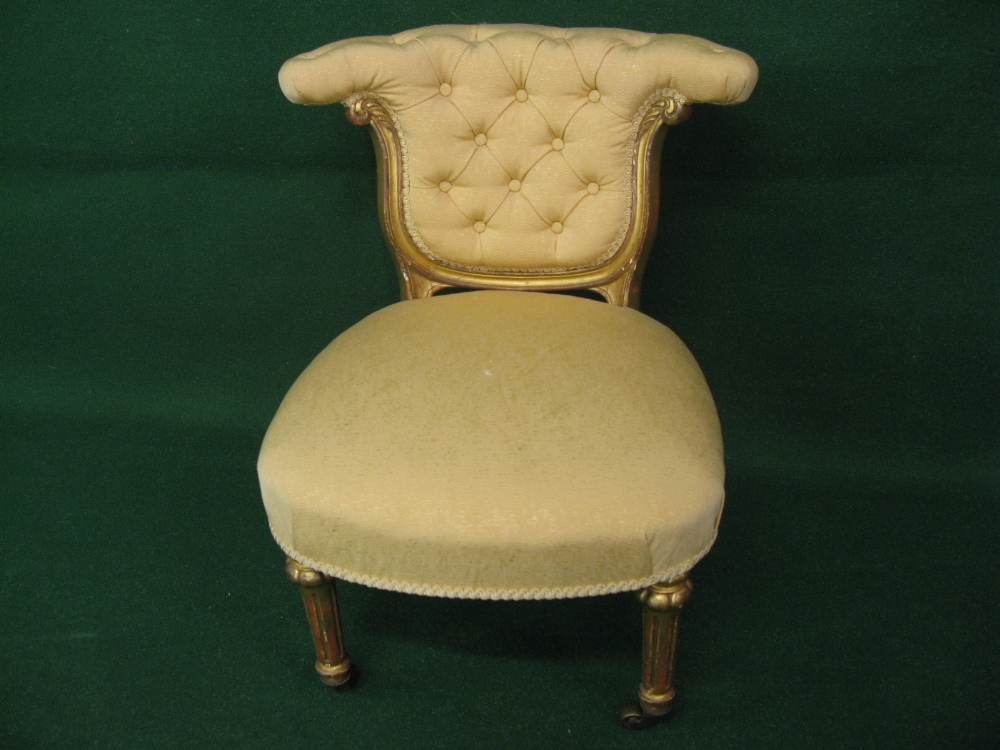 A gilt framed nursing chair with padded button back and padded seat and standing on reeded legs with