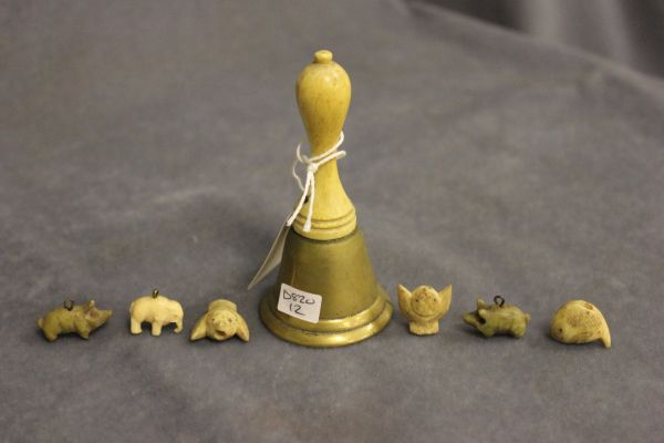 A Small Tin containing small carving bone and ivory and an ivory handled bell