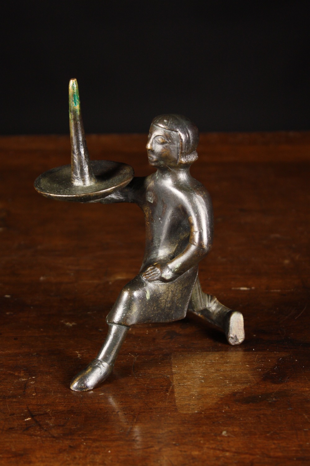 A Gothic Style Figural Bronze Pricket Stick. The candle-spike held aloft by a kneeling man, 6½