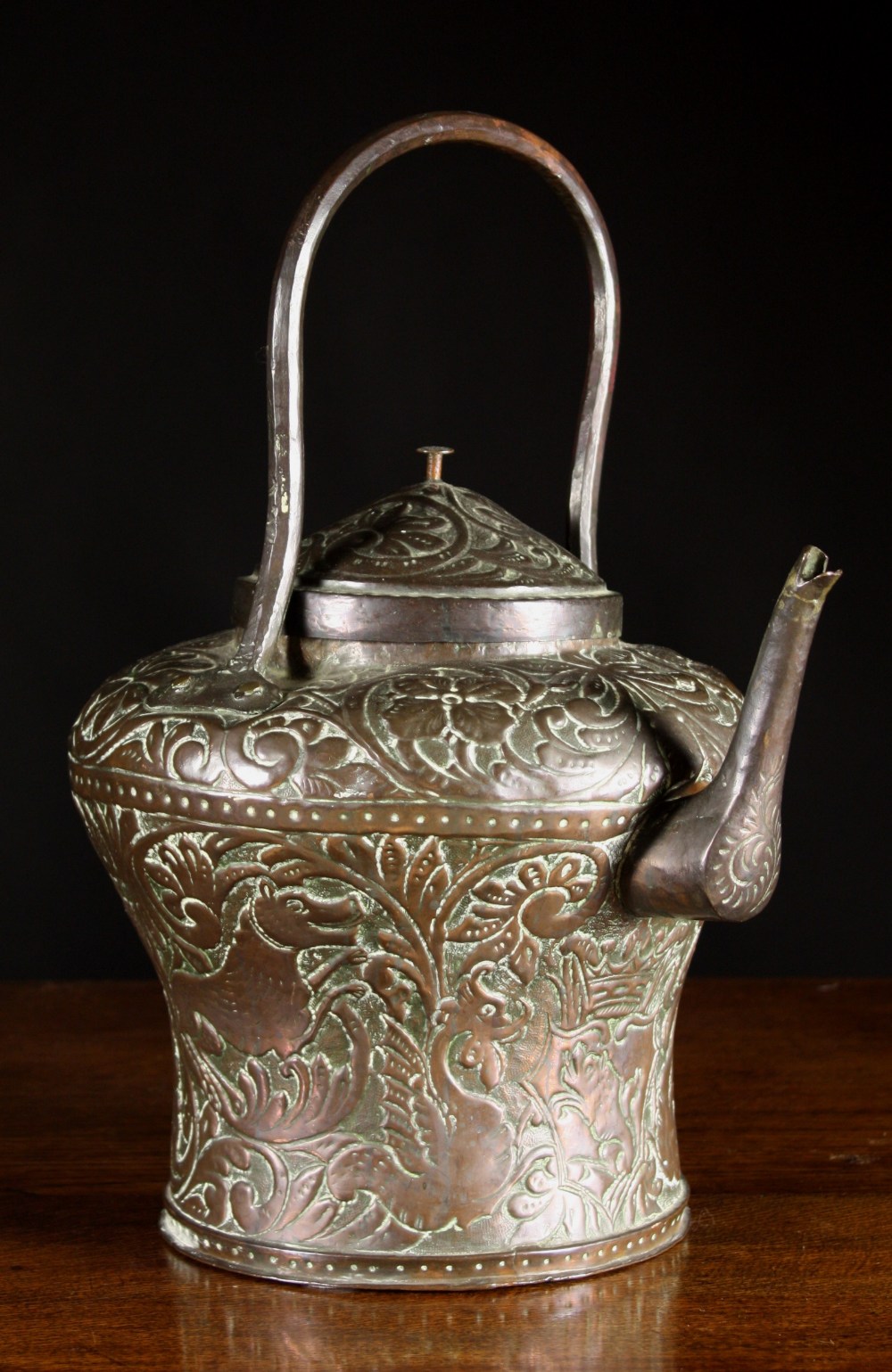 An 18th Century Copper Kettle with repoussé decoration and a wrought iron handle, 16 ins (41 cms) in