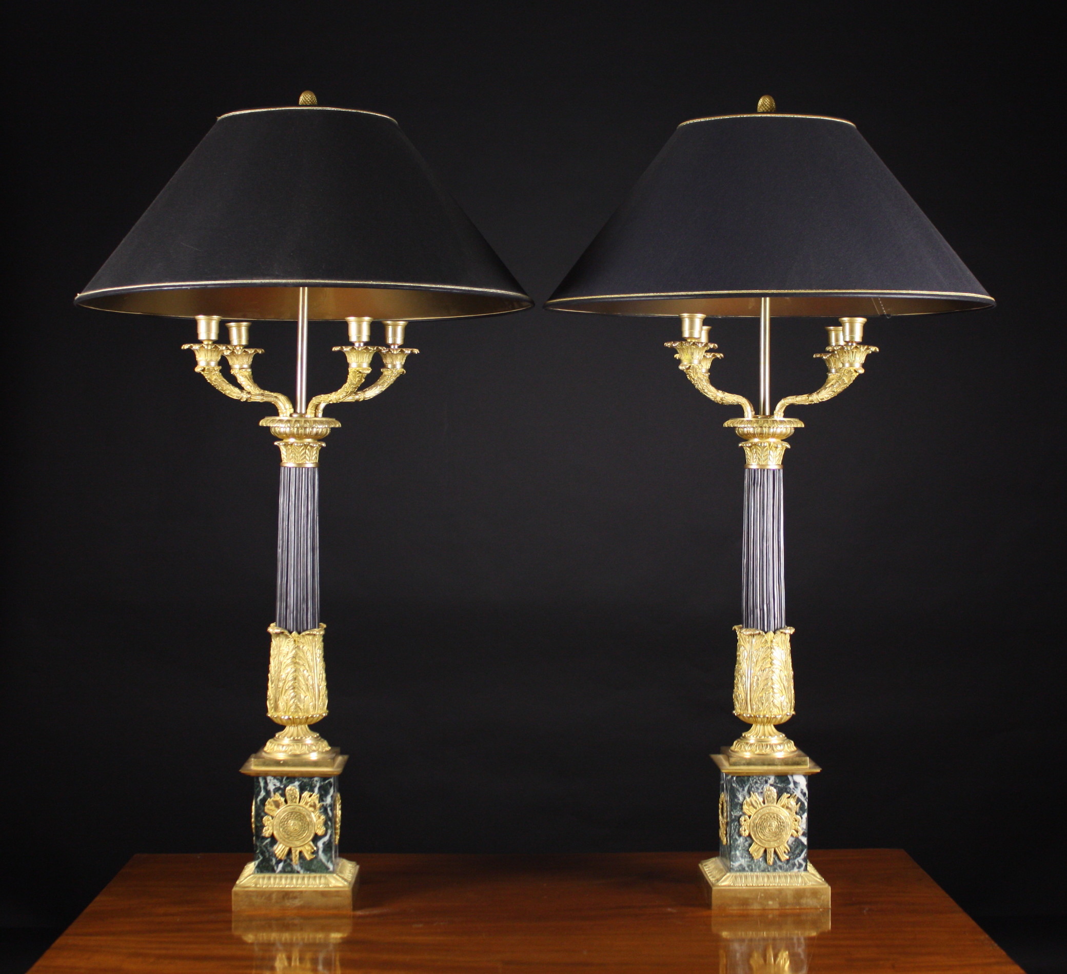 A Pair of Empire Style Bronze Table Lamps.  The black patinated stop-fluted columns enriched with