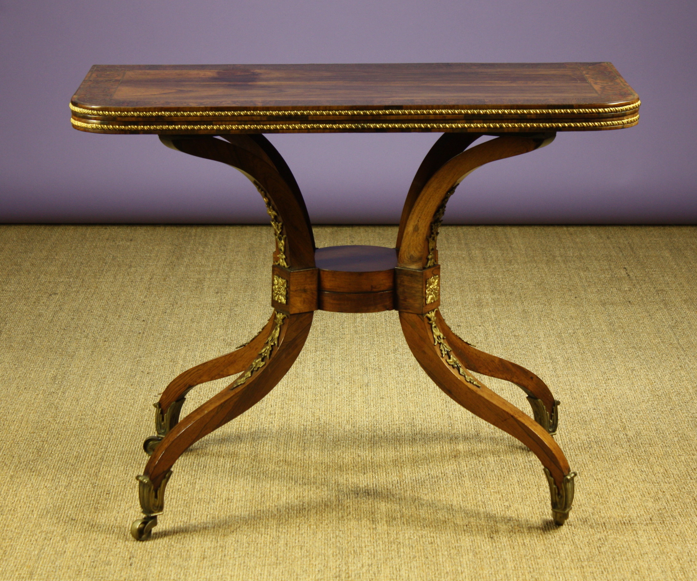 A Regency Rosewood & Brass Inlaid Card table.  The fold over top having rounded corners, a cross-