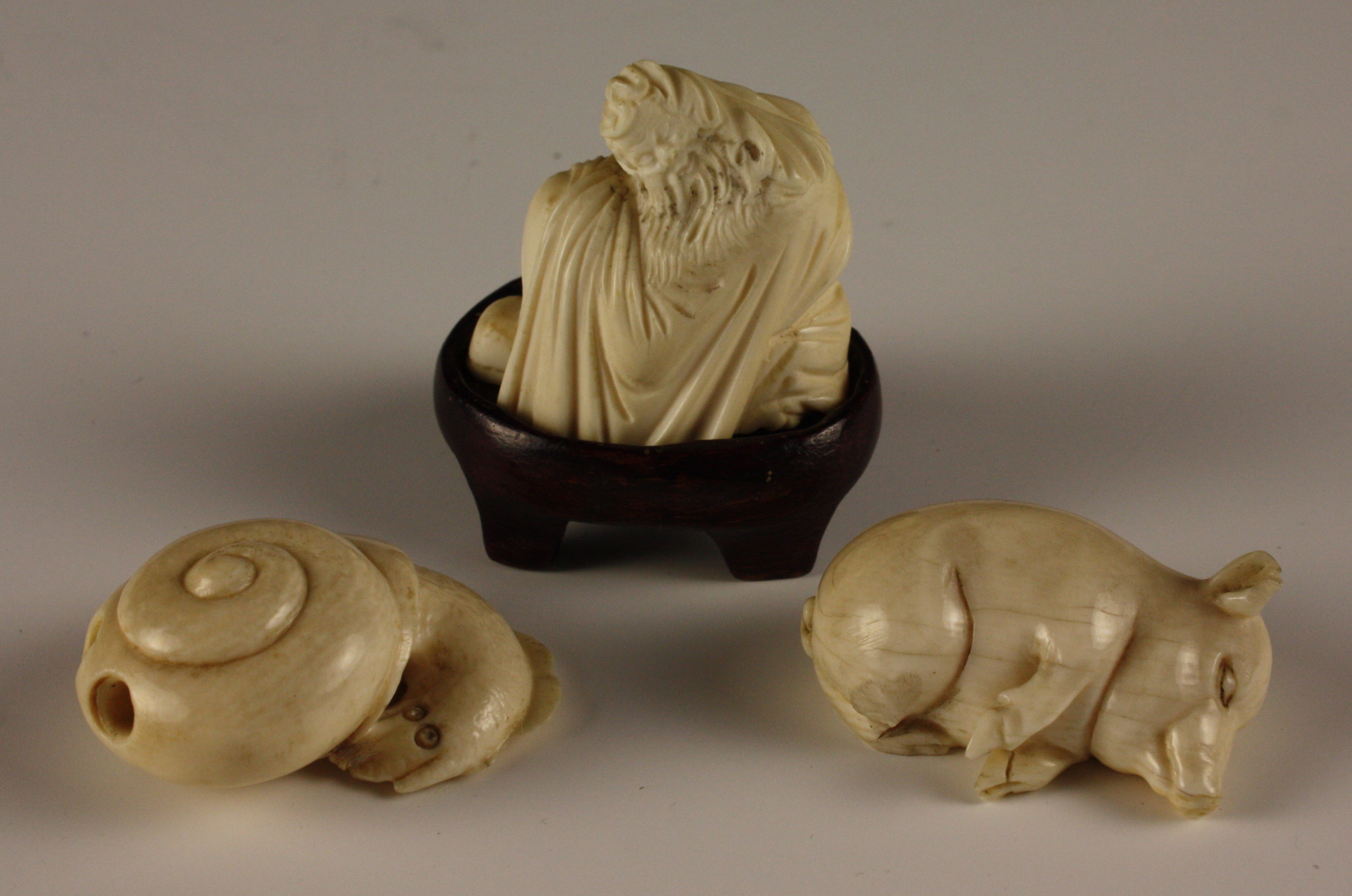Three Small Ivory Carvings: A signed Netsuke carved in the form of a snail, a small sleeping