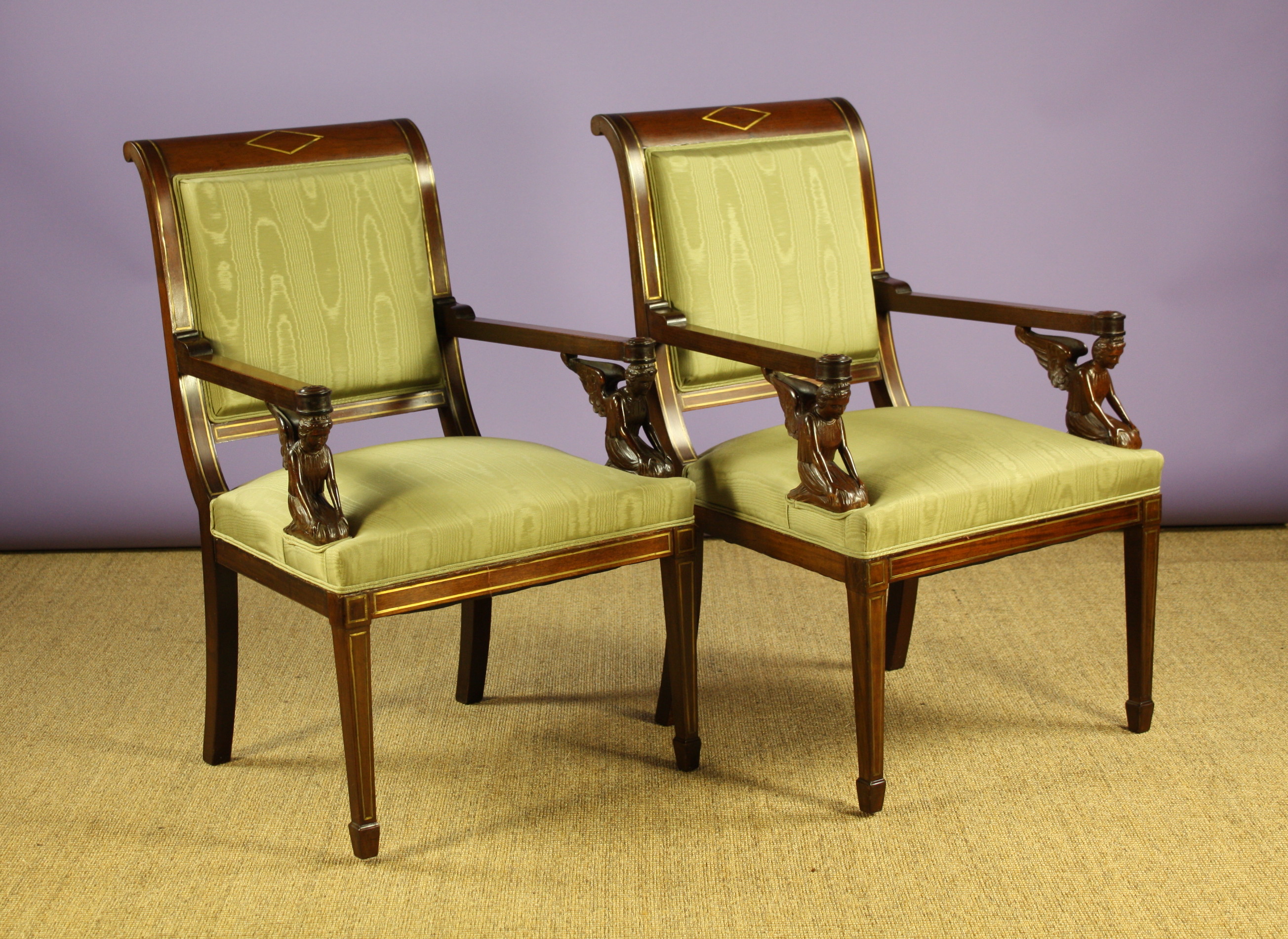 A Pair of Empire Style Mahogany Arm Chairs inlaid with brass stringing.  The square padded backs and