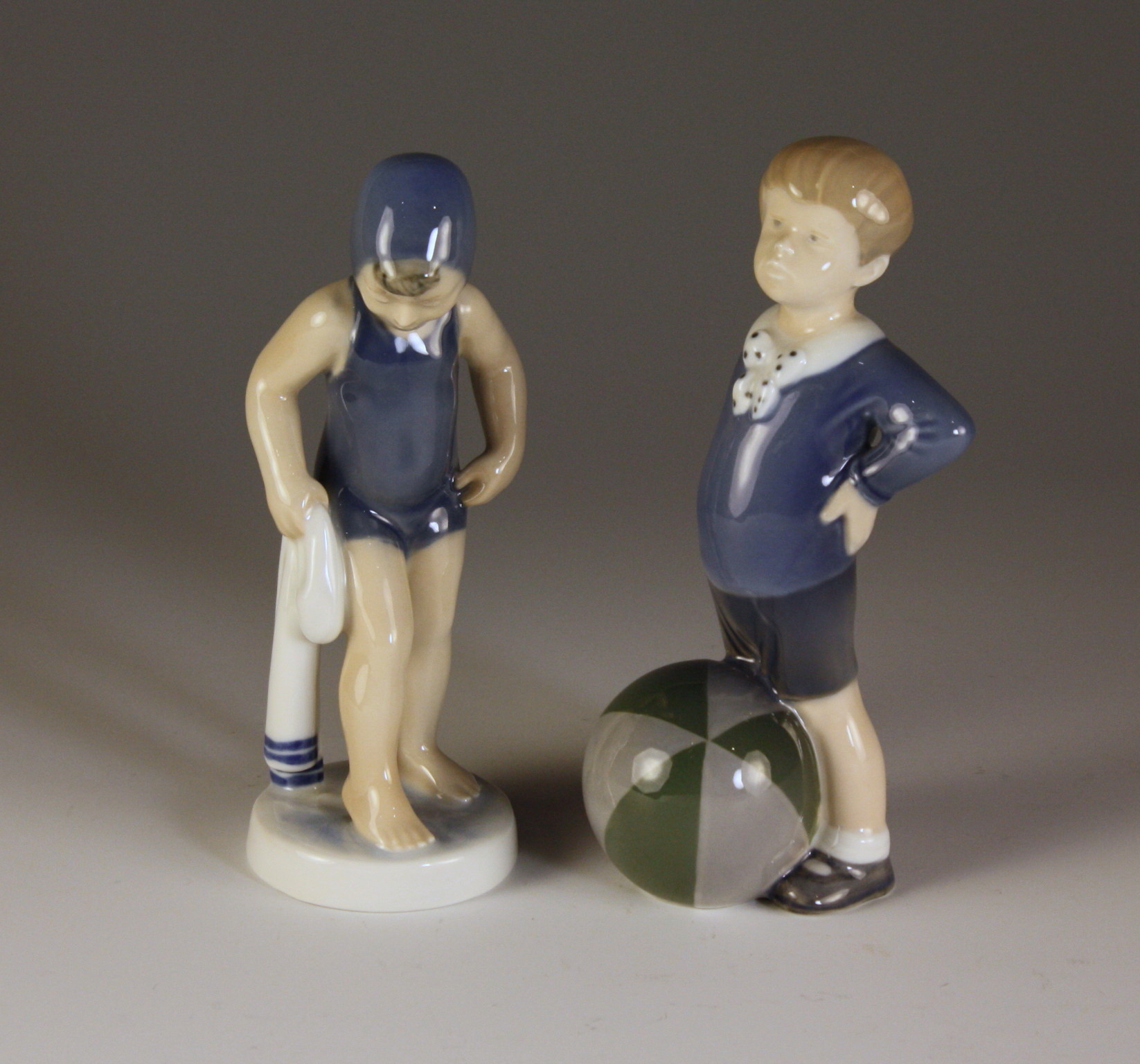 A Pair of Royal Copenhagen Figurines of a boy with ball and bathing girl, 6½ ins (16 cms) in