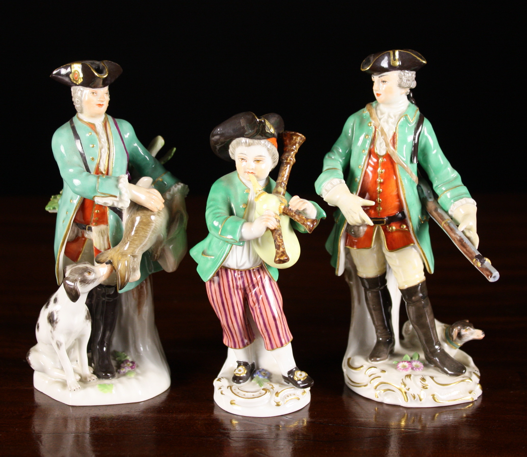 Three Meissen Style Figurines: Two huntsmen and a bagpiper, all wearing gilt trimmed tricorn hats