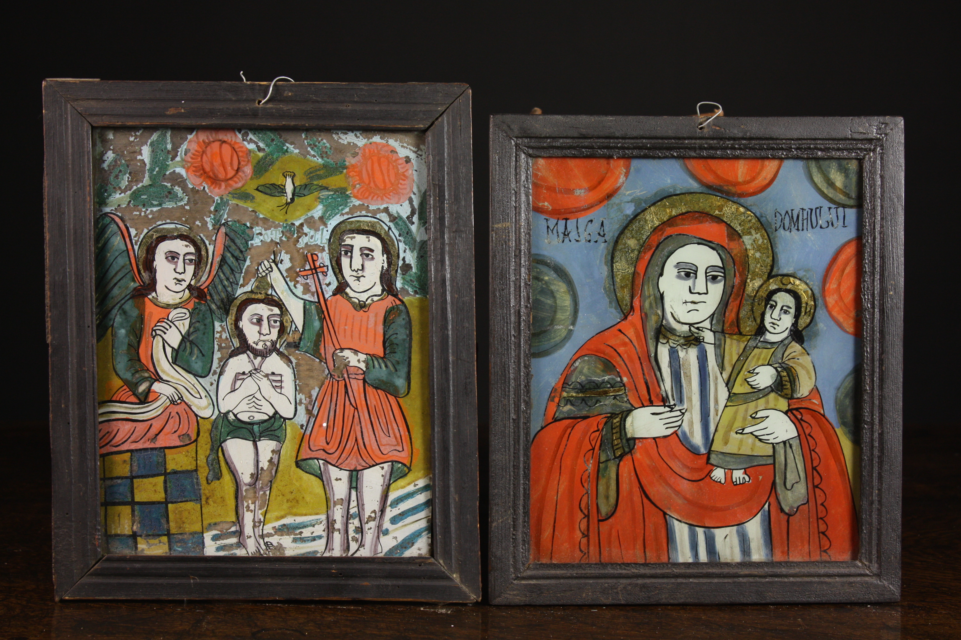 A Pair of Early 19th Century Icons naively painted on glass and set in ebonised wooden frames, 9½