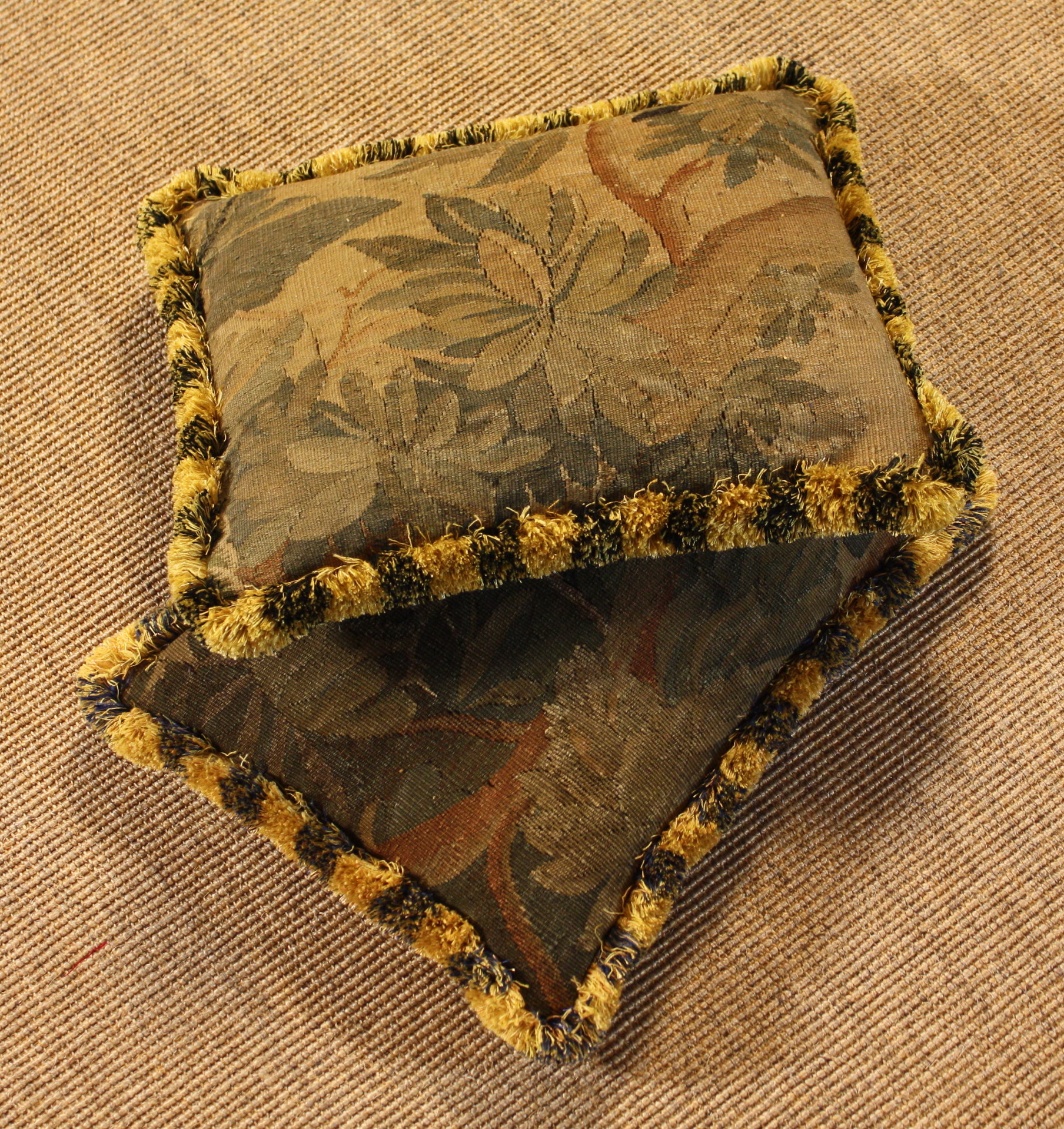 A Pair of Tapestry Cushions.  The 18th century verdure covers edged in gold & dark blue fringing and