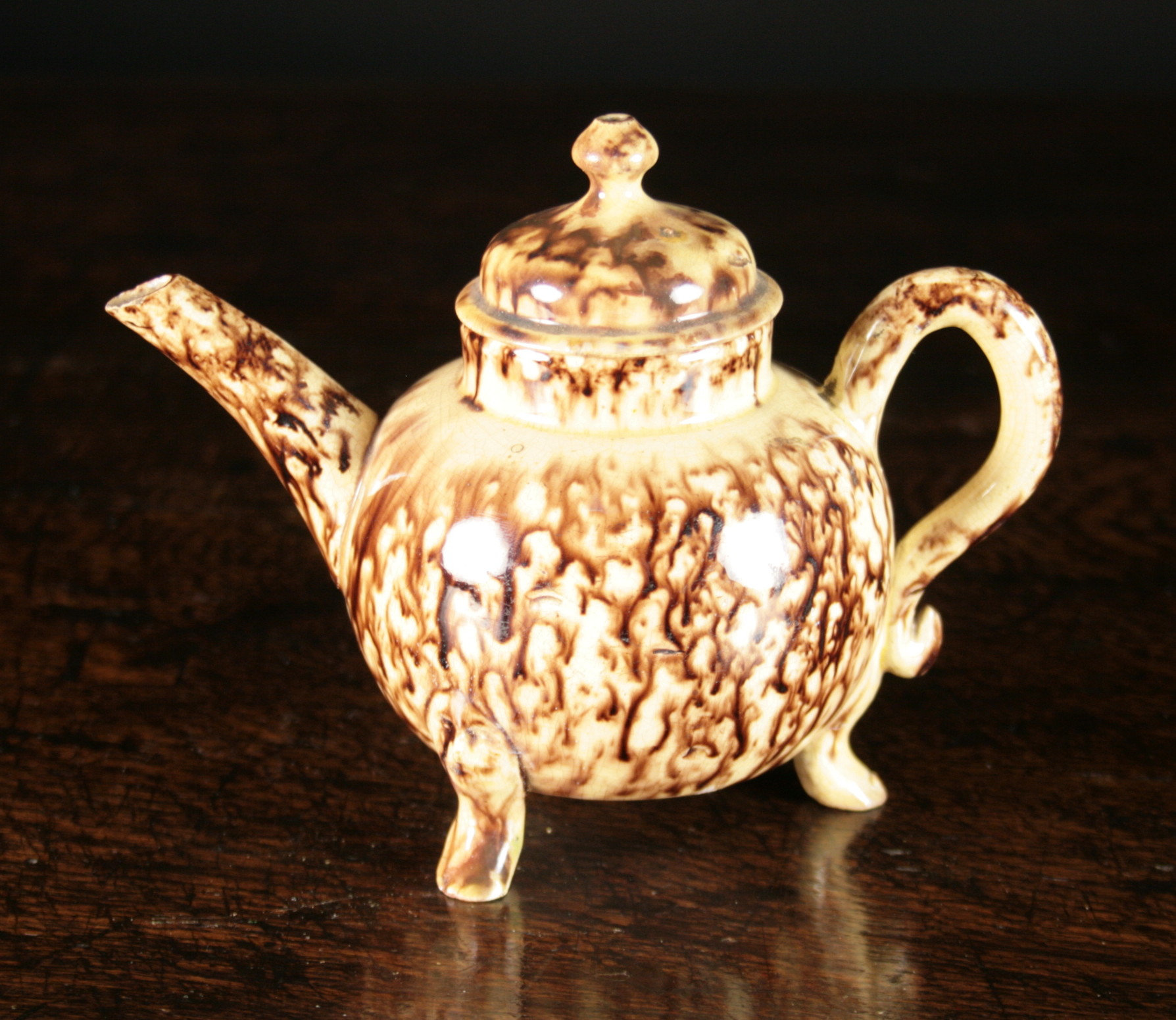 An 18th Century Wheildon Teapot with brown dripped glaze decoration, standing on three feet. (repair