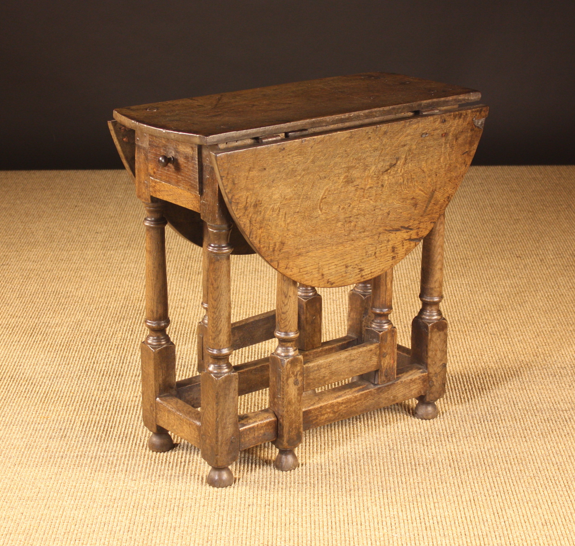 A Joined Oak Gateleg Table of Diminutive proportions.  The oval top above an end drawer standing