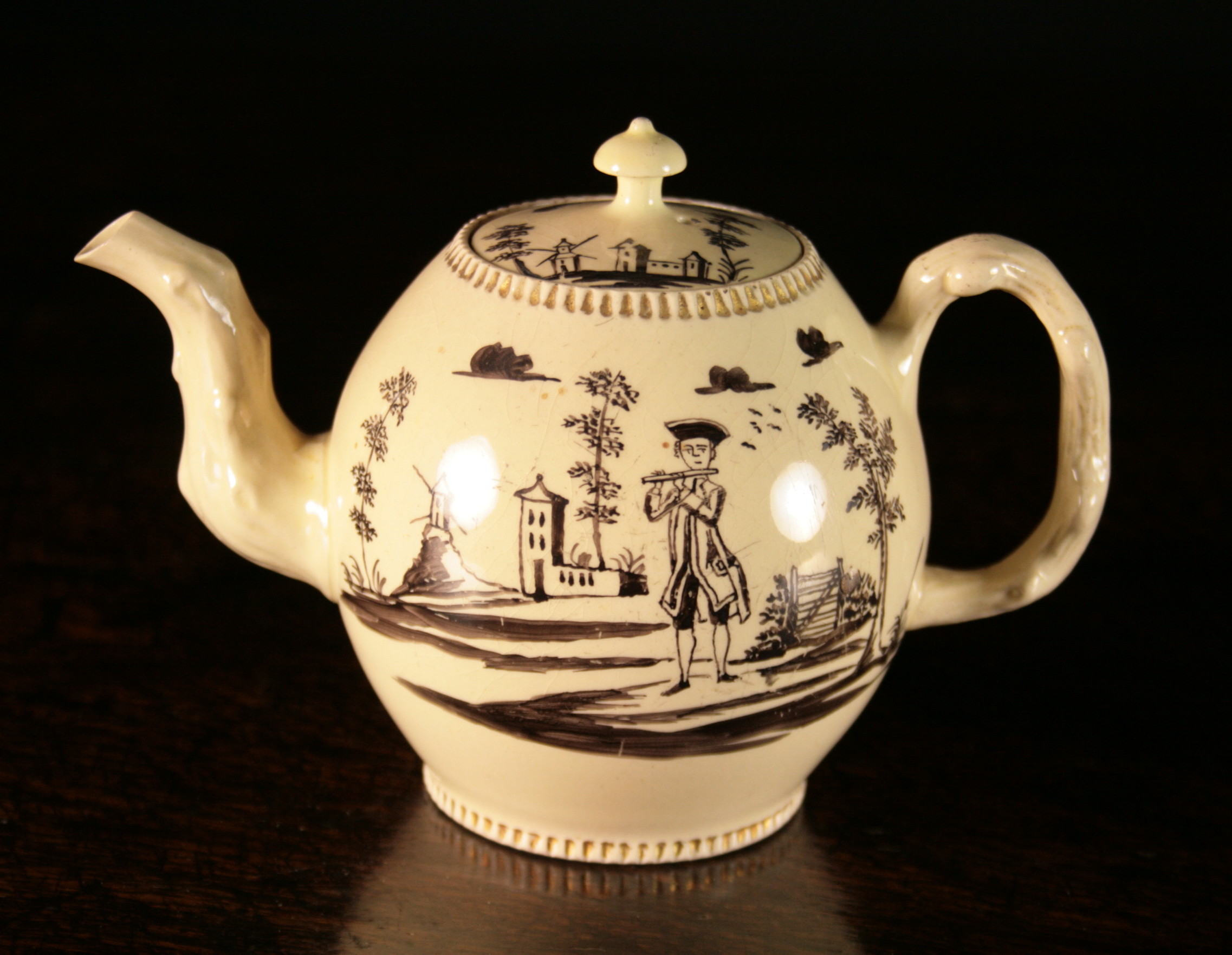 An 18th Century Creamware Teapot.  The globular body painted with a piper in landscape and having