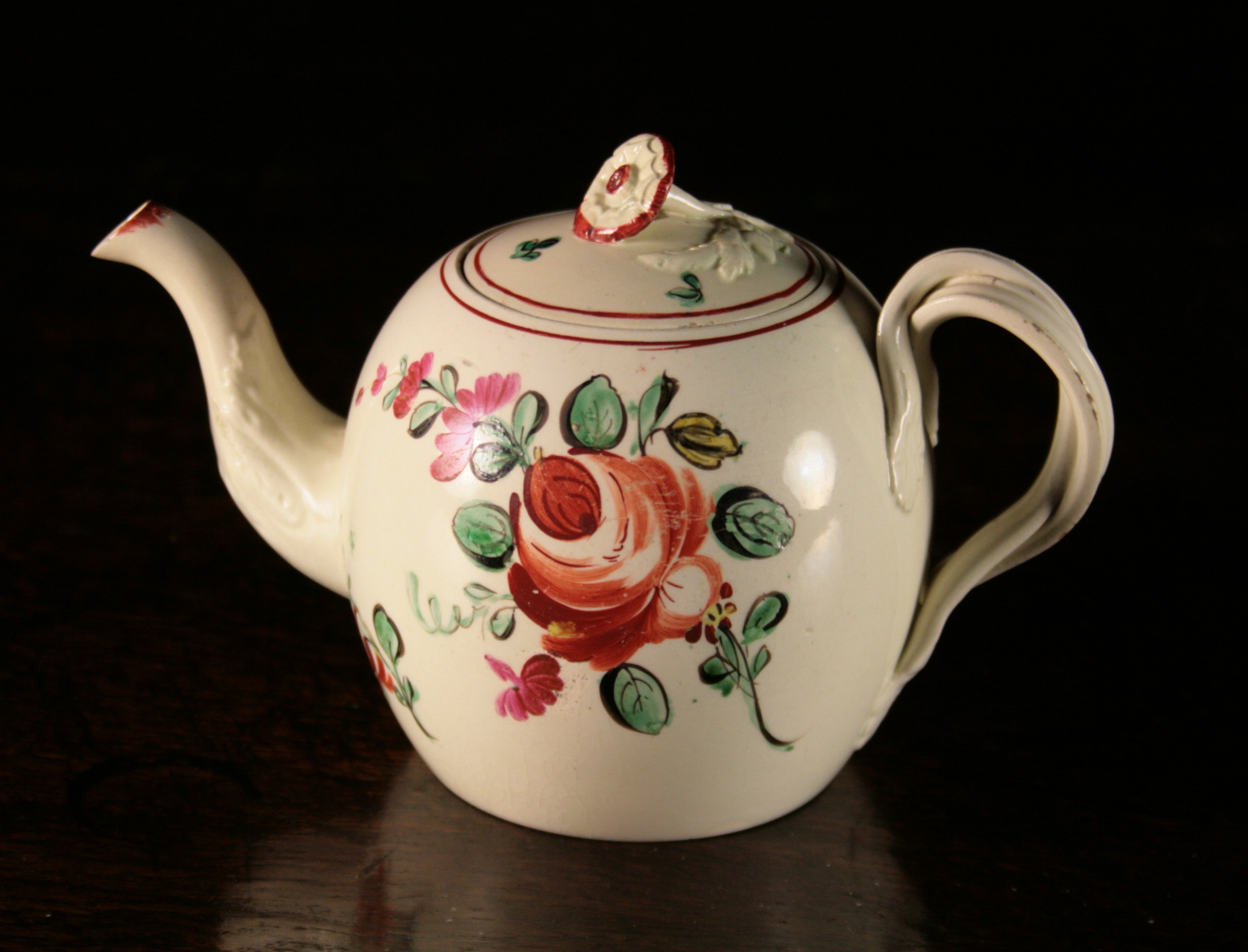 An 18th Century Creamware Teapot.  The globular body decorated with roses and having an entwined
