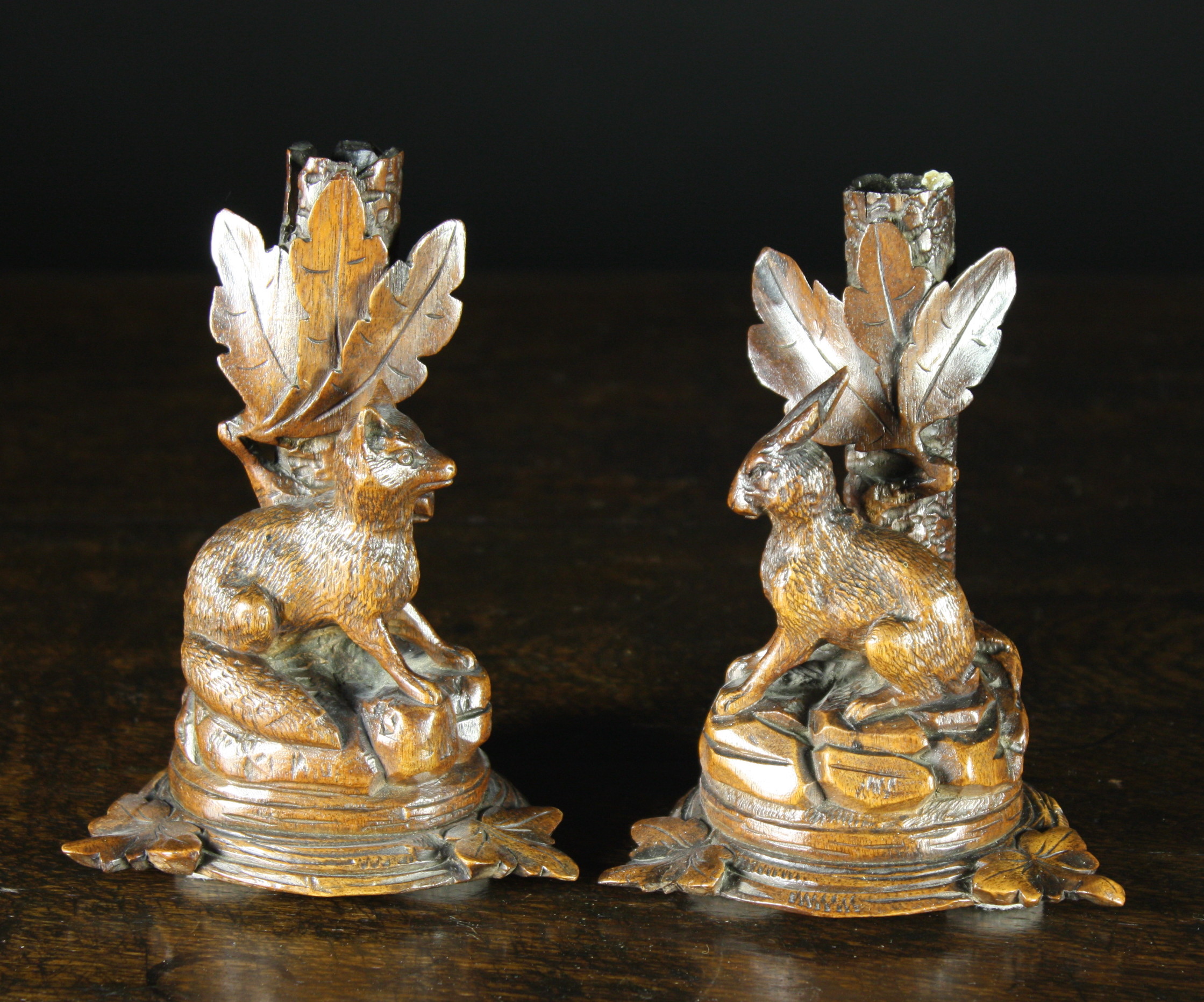 A Pair of 19th Century Black Forest Candlesticks carved in the form of tree trunks sprouting leaves,