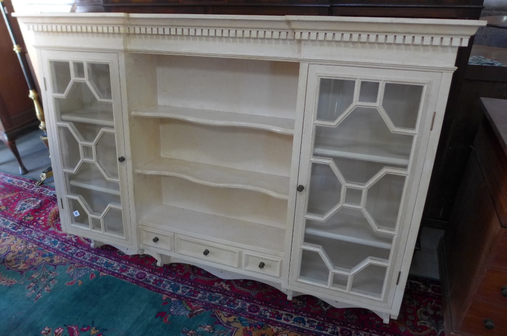 A painted wall hanging unit with shelves and two side cupboards with glazed doors made in 1995