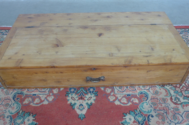 A pine storage chest on wheels which would fit under a bed - Height 22 cm x Width 120 cm