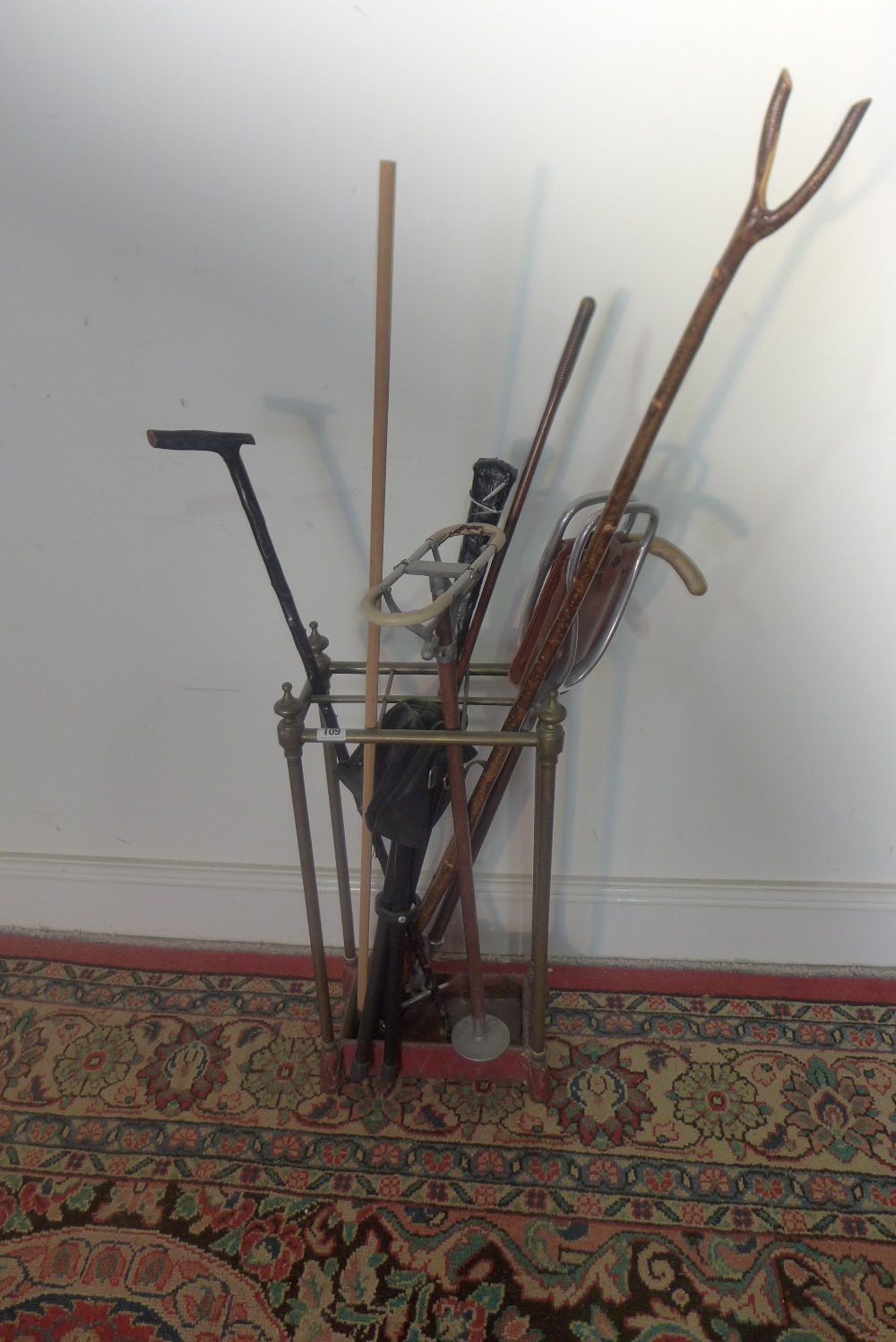 A six section brass and cast iron stick stand with a selection of sticks, shooting sticks etc