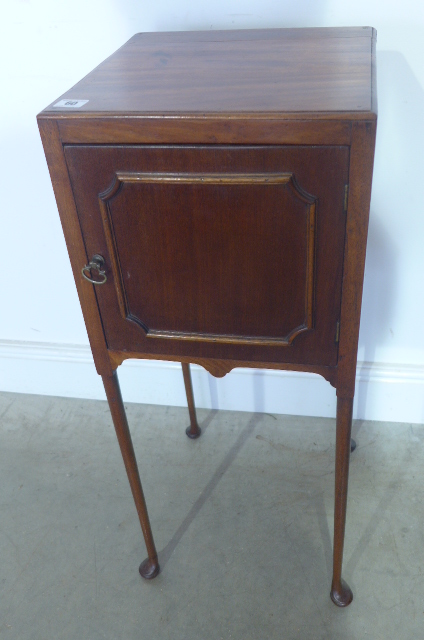 A mahogany bedside cupboard with slender turned legs and pad feet