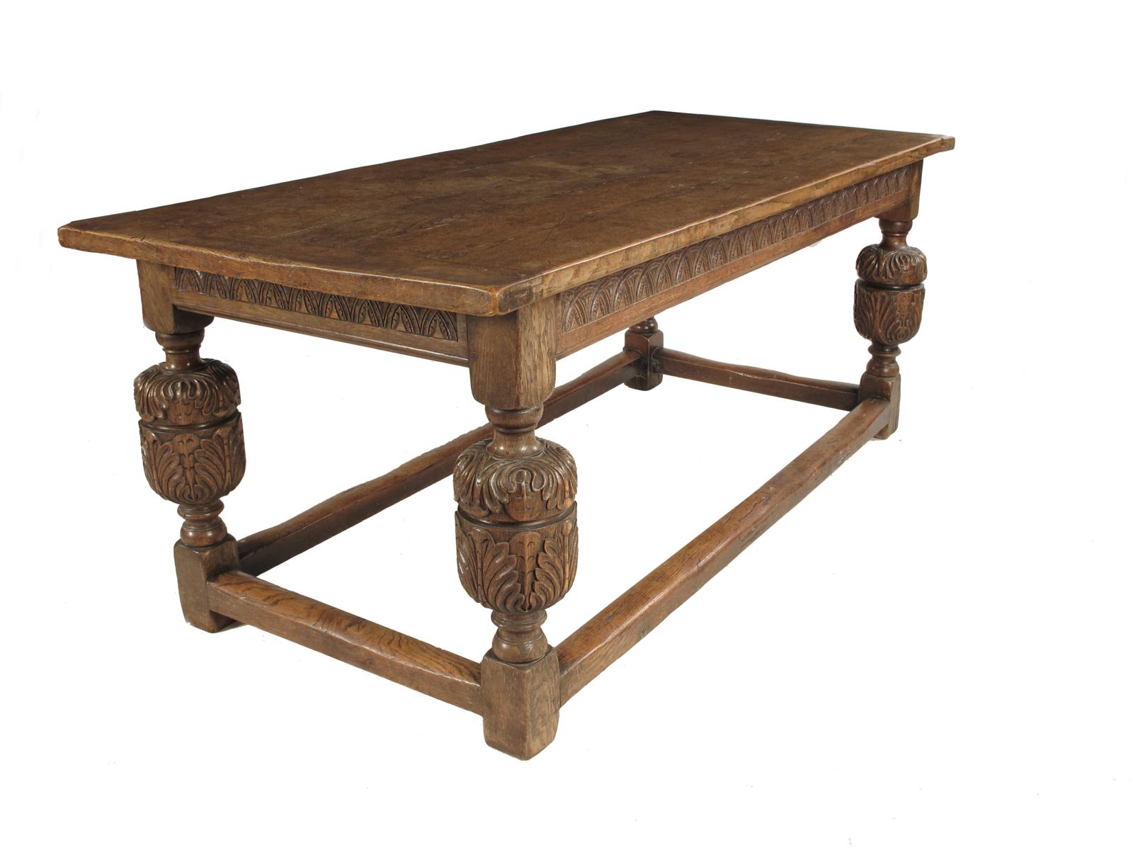 A joined oak refectory table, in 17th century style, with a cleated boarded top, above a carved
