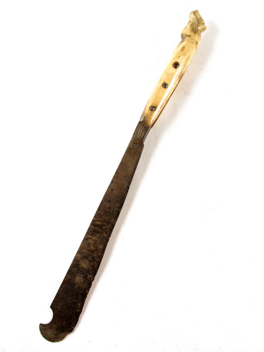 A Malay steel bladed knife, with a bone handle carved an animal head, 23½in (59.6cm) long.