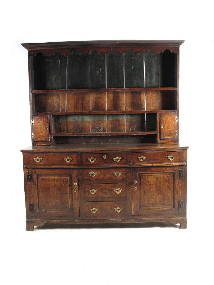 A mid 18th century oak dresser, the raised plate rack with a pair of cupboard doors marquetry inlaid