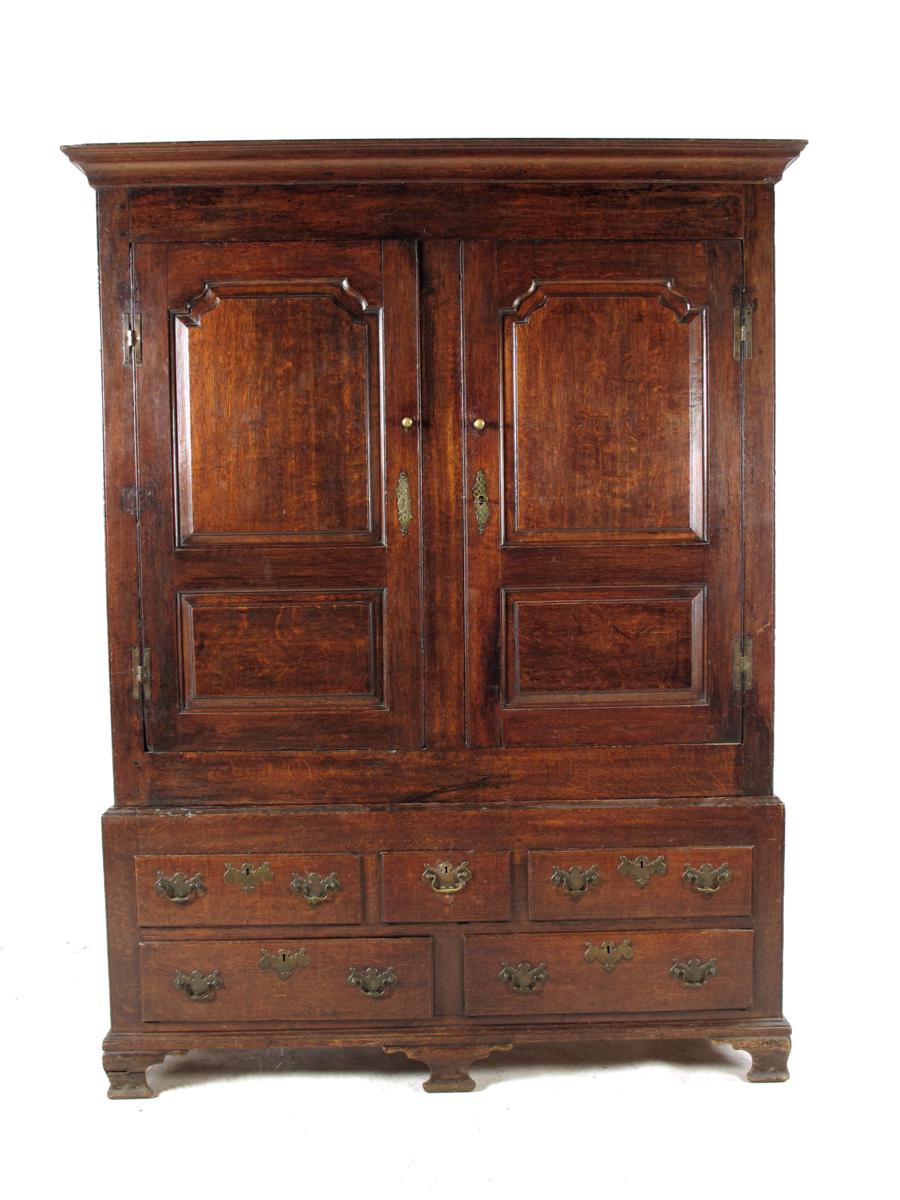 A George II oak press cupboard, with a detachable cornice, above a pair of fielded panel doors