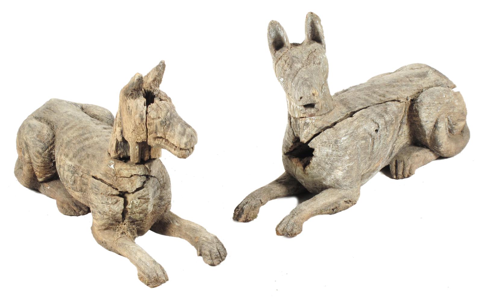 A pair of carved and weathered wood recumbent hounds, 17in (43cm) high, 29½in (74.8cm) wide, 8in (