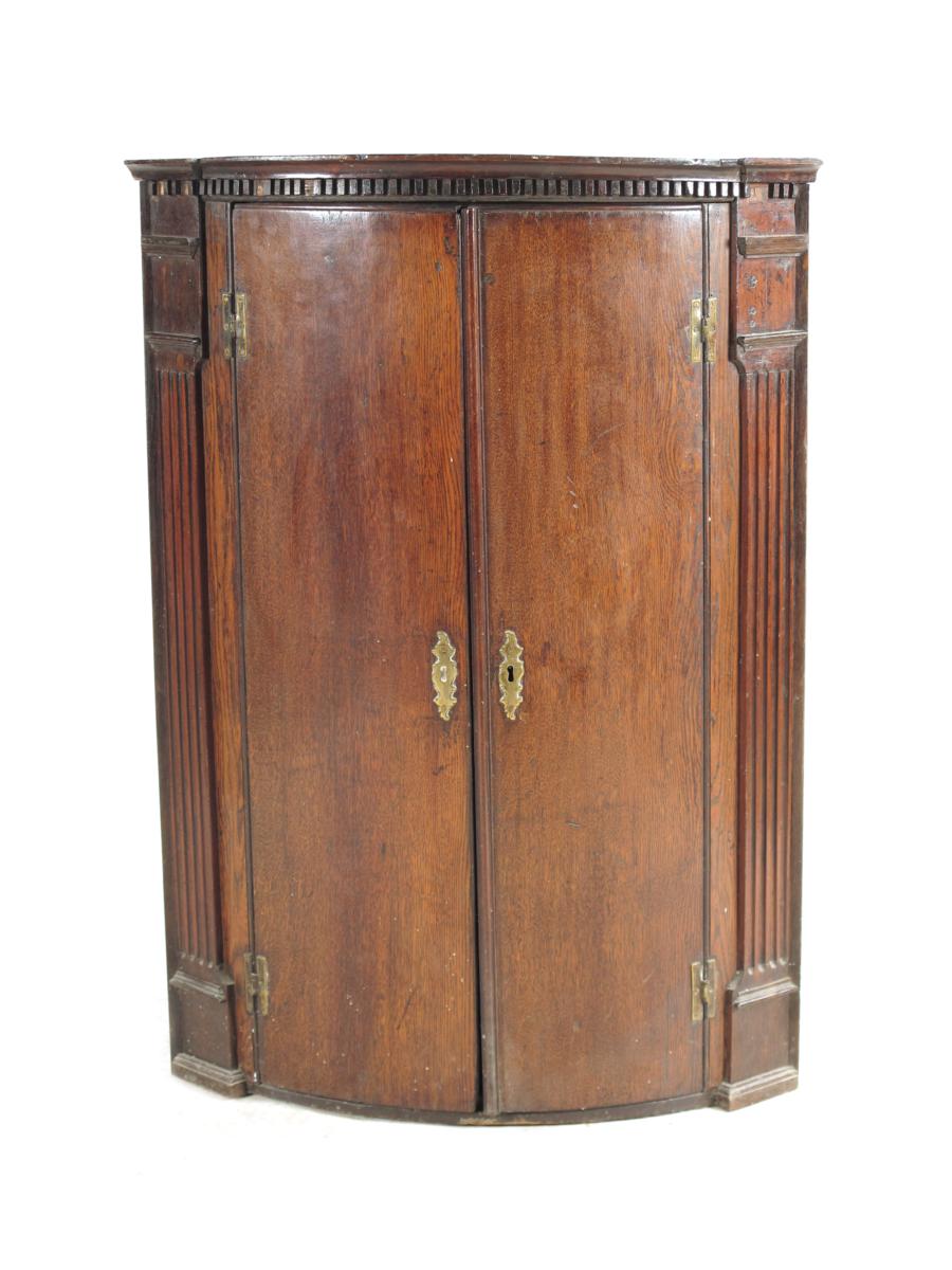 A George II oak bowfront hanging corner cupboard, the interior with three shelves, 39½in (100cm)