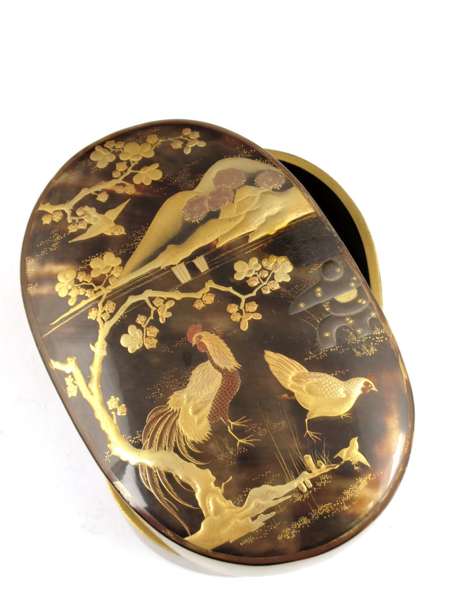 ? A Japanese tortoiseshell and lacquer oval box and cover, gilt decorated fowl beside a prunus