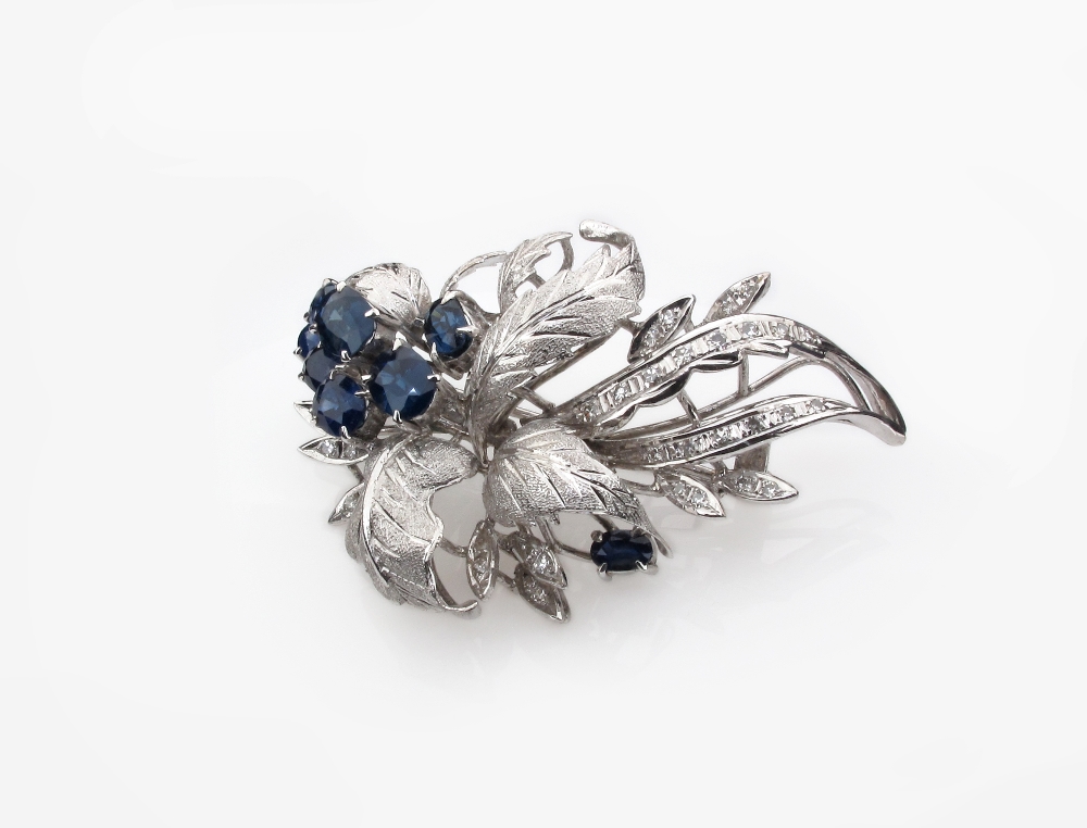 A sapphire and diamond foliate spray brooch, set with eight oval shaped sapphires and circular cut