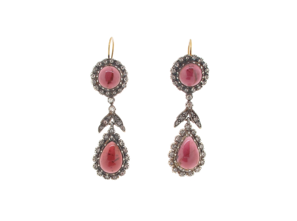 A pair of garnet and diamond drop earrings, the pear shaped cabochon garnets are set within a