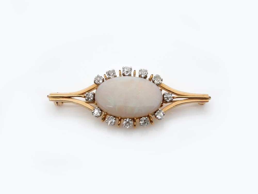 An opal and diamond brooch, the solid white opal is set within a surround of twelve circular cut