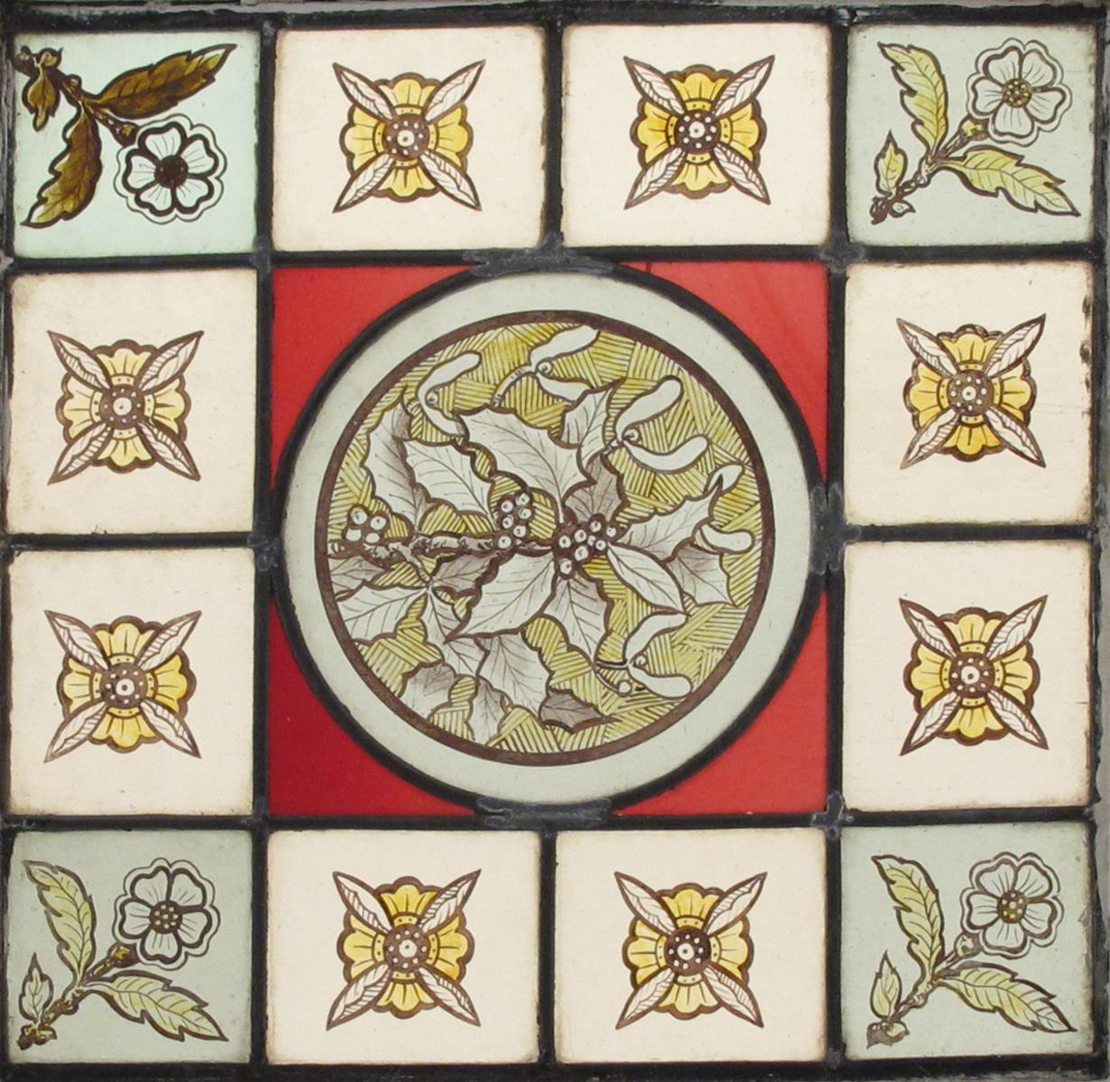 A small stained glass window, decorated with a central roundel of holly, inside panel border of