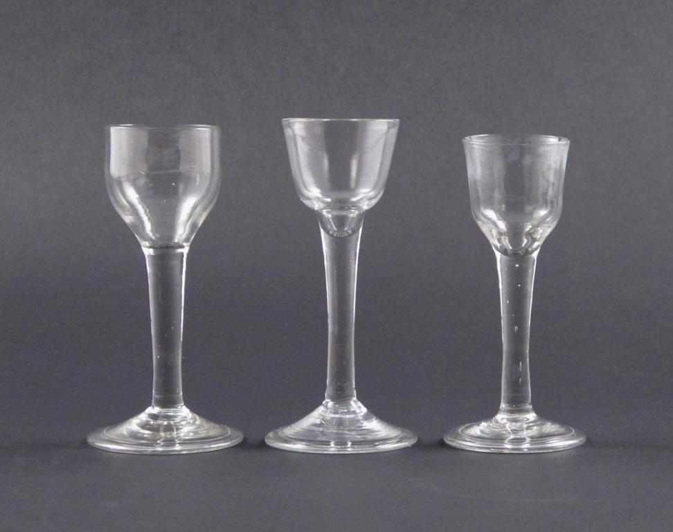 Three wine glasses mid 18th century, with ogee-shaped bowls all raised on plain stems above folded