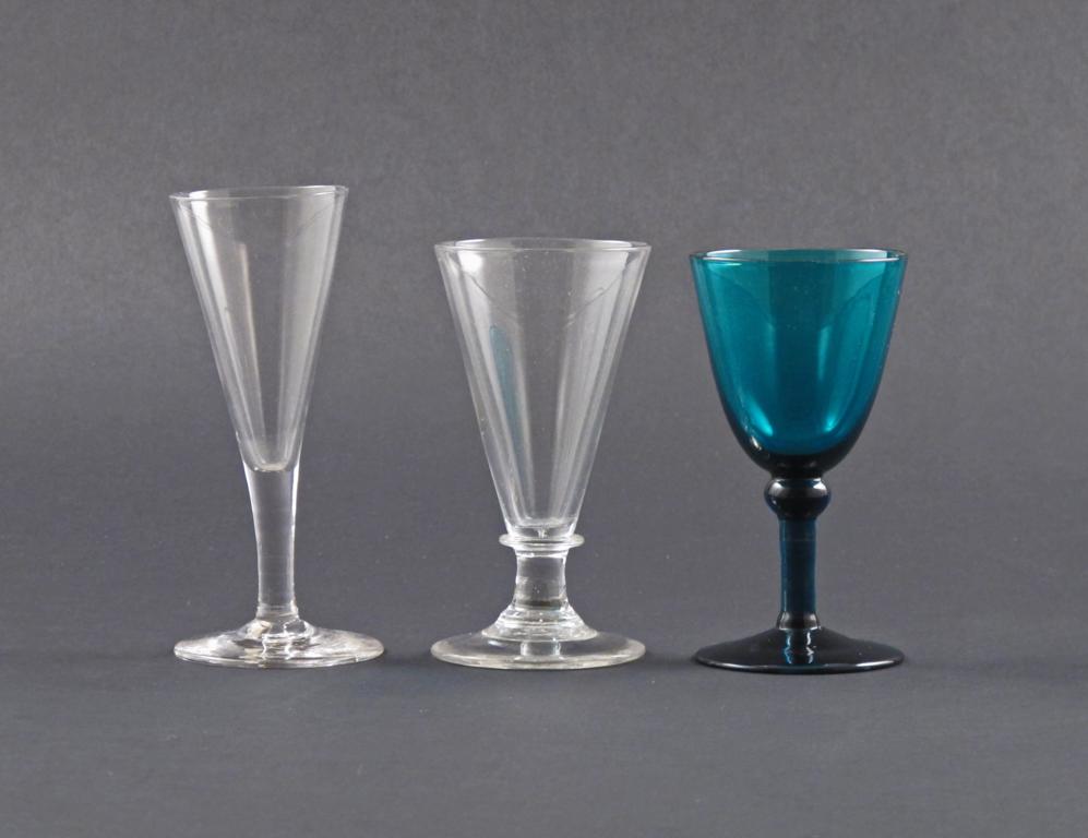 Two ale glasses 18th century, raised on short stems, and a green glass goblet with a cushion knop