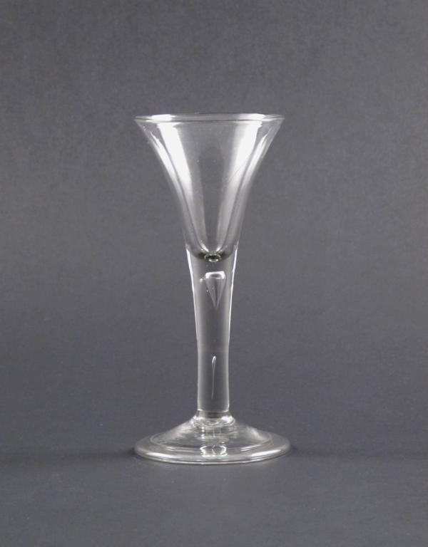 A large wine glass mid 18th century, the drawn trumpet bowl raised on a teardrop stem above a folded