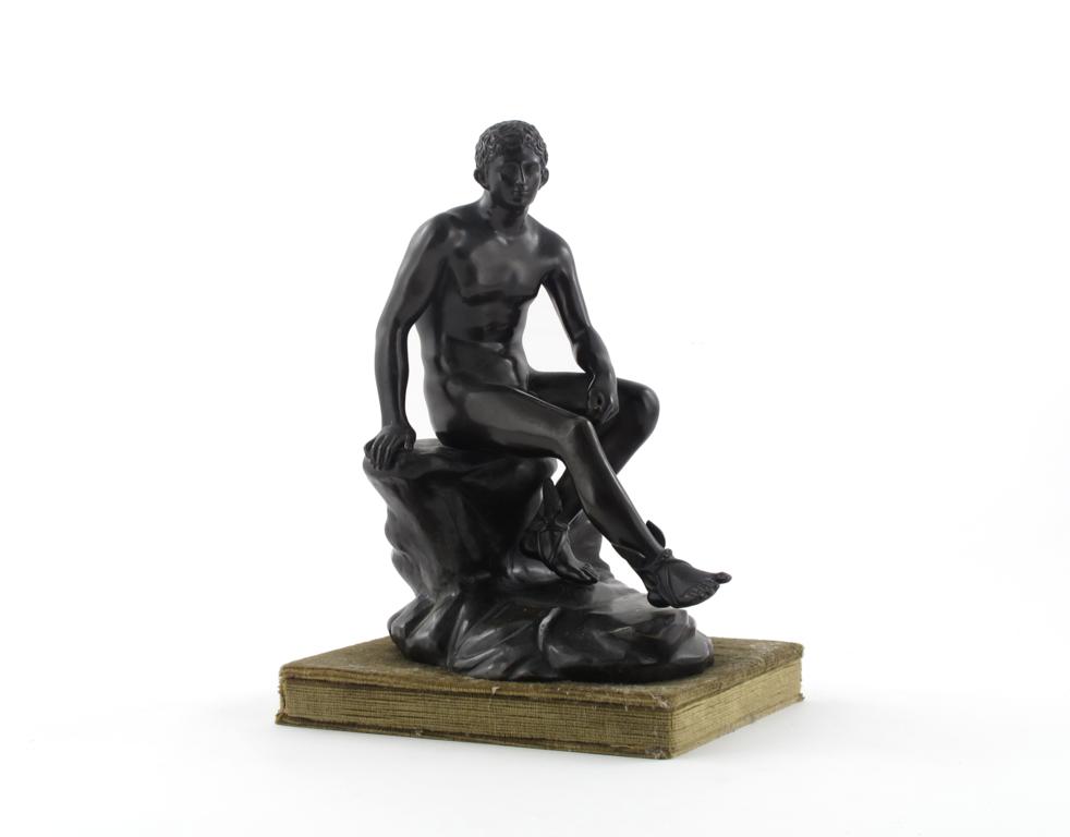 A bronze figure of Mercury, after the antique, seated on a rocky outcrop and wearing winged sandals,