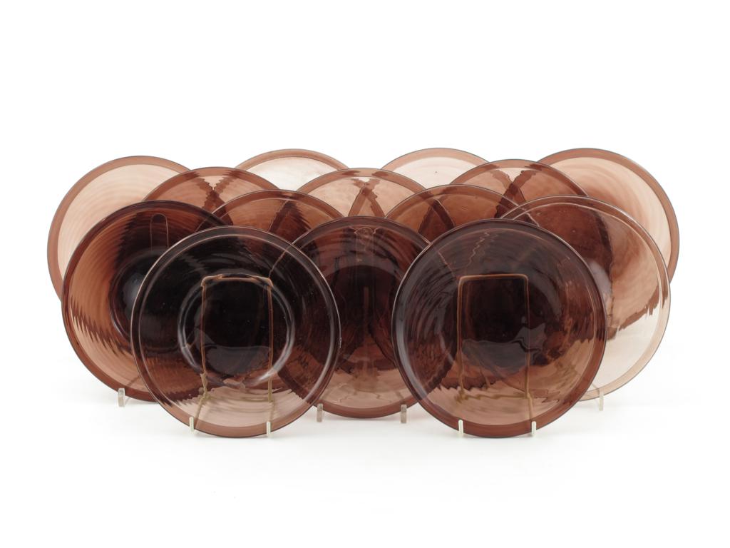 Fourteen amethyst glass plates, lightly moulded with a spiral design, the rims folded, 19cm. (14)