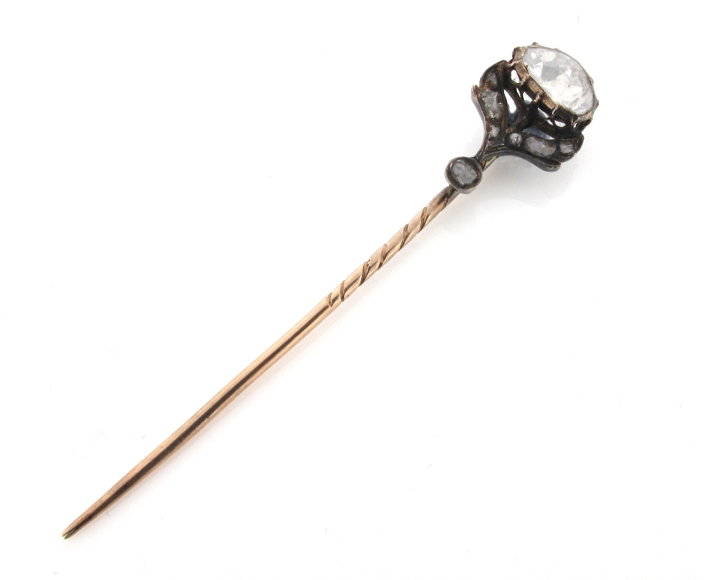 A diamond set gold stick pin, the large closed back rose cut diamond is set with smaller diamonds