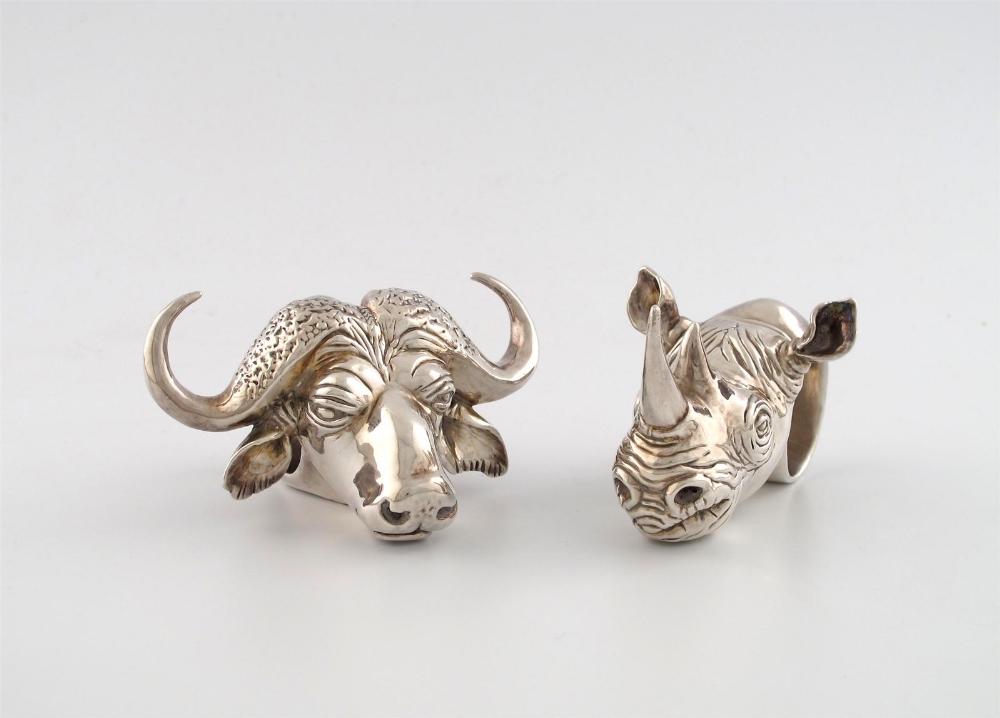 A pair of novelty metalware napkin rings, one modelled as a rhino`s head the other as the head of a