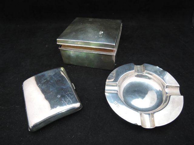 A silver cigarette case of square cut form with rising lid, a circular silver ashtray and a silver