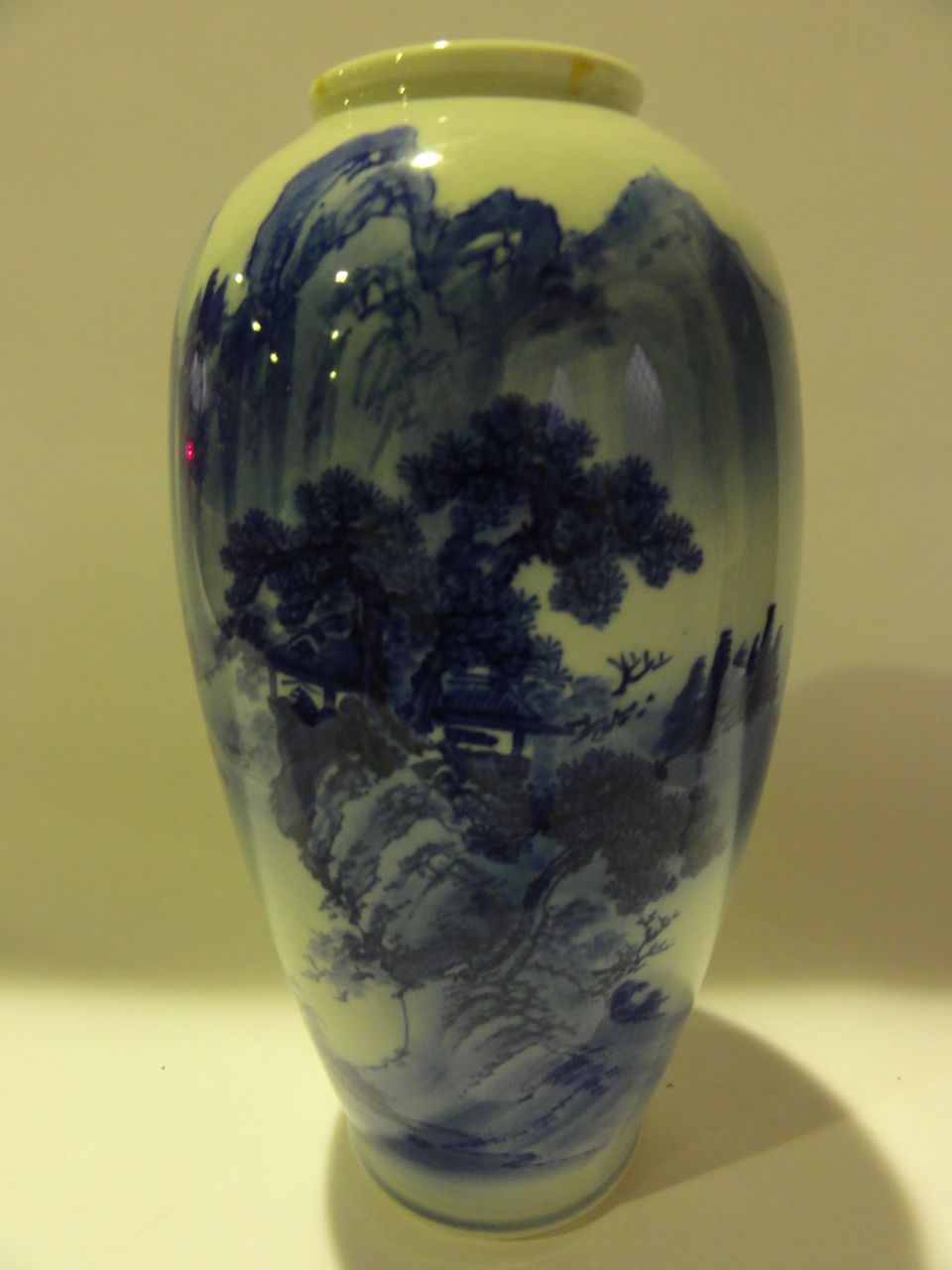 An oriental blue and white vase decorated with mountain scenes with marks to base